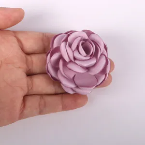 Détail de fleur de camélia en tissu violet, accessoire DIY fait main pour broche, chapeau ou vêtement.