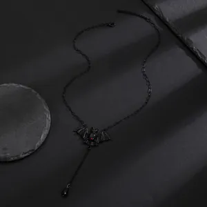 Μακροεντολή λεπτομέρεια μαύρου γοτθικού κολιέ νυχτερίδας με κόκκινη πέτρα και μενταγιόν.