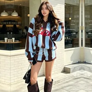 Female model in a blue and brown striped knit sweater set posing outdoors in a city.