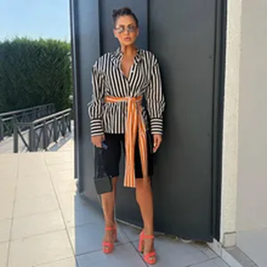 Fashionable black and white striped blouse with vibrant orange tie and cycling shorts