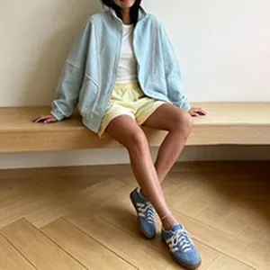 Detailed view of oversized light blue zip-up jacket featuring stylish contrast piping