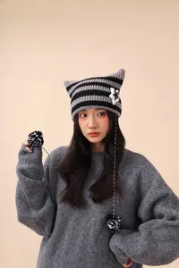 Cute grey striped cat ear beanie with star patch and dangling pom poms on an Asian model