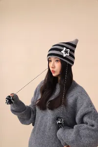 Detailed view of handmade striped knit beanie with cute cat ears, star patch and pom-poms