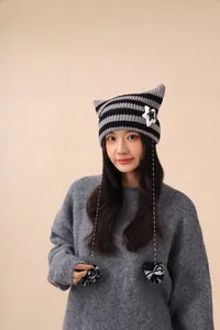 Close-up of a striped knit cat ear hat with plush star detail and fuzzy pompoms