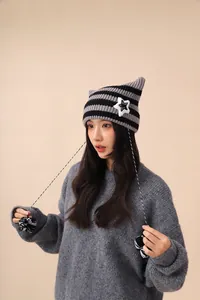 Close-up of a cute striped cat-ear knit hat with star patch and long pom-pom cords