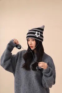 Cute cat ear striped knit hat with white star patch and fluffy pom poms detail on ropes