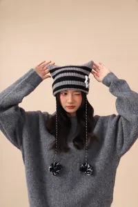 Close-up of a striped cat-ear beanie with star patches and cute pompoms for women.