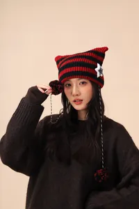 Model wearing a red and black striped cat ear knit hat with star patch details