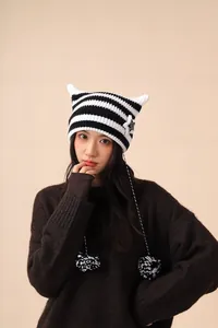 Close-up detail of a striped knitted beanie featuring cute cat ears and star accents