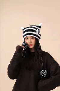 Close-up of a striped cat-ear beanie with star detail and pom-poms.