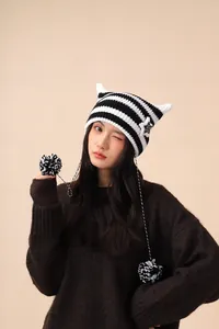 Detailed macro view of a cute black and white striped cat ear beanie with pom-poms