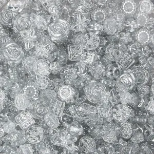 Close-up view of mixed clear acrylic beads, assorted shapes for DIY jewelry making.