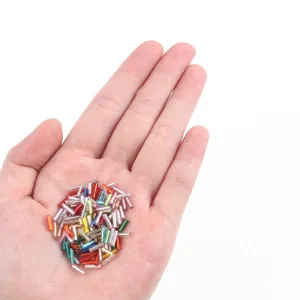 Detailed macro view of multi-colored 2x7mm silver-lined glass bugle beads in hand