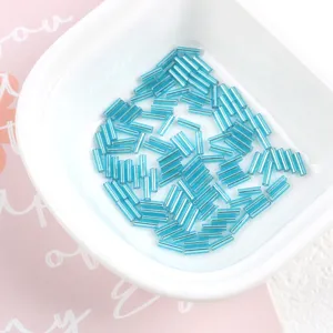 Macro view of blue 2x7mm silver-lined glass bugle beads for DIY jewelry in a white bowl