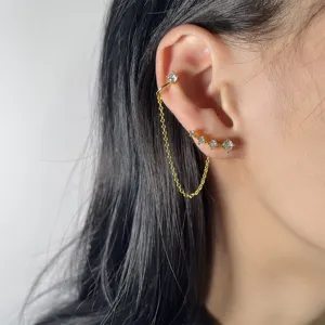 Elegante set di ear cuff e orecchini con catena dorata e zirconi cubici scintillanti.