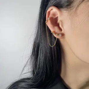 Dettaglio ravvicinato di un ear cuff in zircone brillante con catena dorata e perno