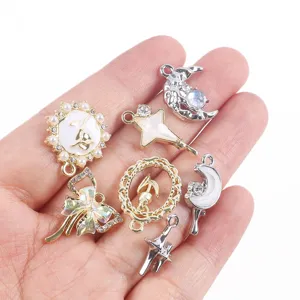 Hand showing various DIY alloy pendants like moon star and bow for jewelry making