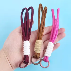 Close-up of three hand-woven braided phone lanyards in burgundy brown and pink