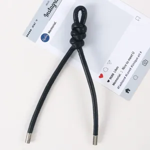 Detailaufnahme des schwarzen geflochtenen Lederbandes als schicker Taschenanhänger.