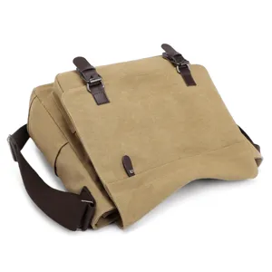 Detail view of a men's khaki canvas messenger bag with brown leather buckle straps