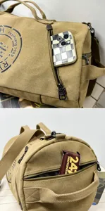 Close-up of side zipper pocket on khaki canvas duffel bag showing storage for small items