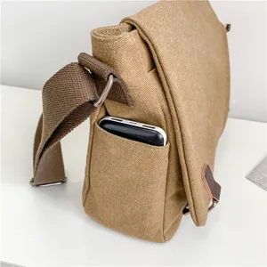 Khaki canvas messenger bag for men with functional side pocket for power bank.