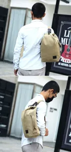 Back view of the khaki canvas sling bag worn by a male model in an urban setting.