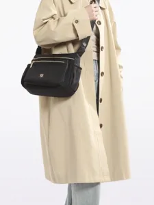 Elegant black multi-compartment crossbody bag for women styled with a beige coat