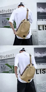 Close-up of a large khaki canvas sling bag for men worn in a casual street style setting
