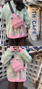 Close-up detail of a cute pink frog cartoon crossbody bag worn by a girl outdoors.