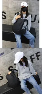 Large black pebbled leather backpack held by model in casual urban studio setting