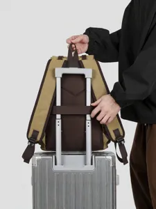 Khaki canvas travel backpack with luggage strap secured on a silver suitcase handle