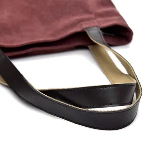 Detailed view of burgundy canvas tote bag featuring black and khaki contrast straps.