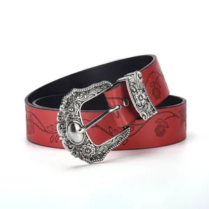 Close-up of a vintage red embossed belt featuring a detailed floral carved silver buckle.