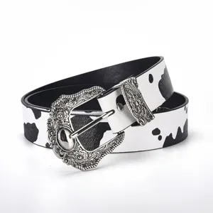Close-up of vintage engraved metal buckle on cow print patterned leather belt