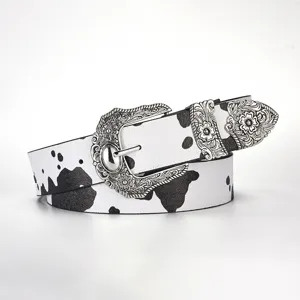 Detail of western vintage belt featuring black and white cow print and ornate silver buckle.