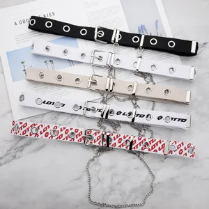 Primer plano de cinturones con ojales de estilo punk y cadenas colgantes de plata.