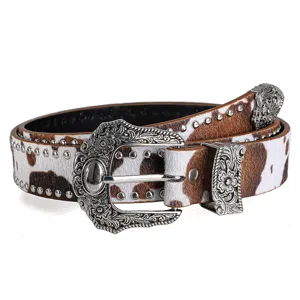 Western cow print leather belt with vintage floral engraved metal buckle and metal studs detail.