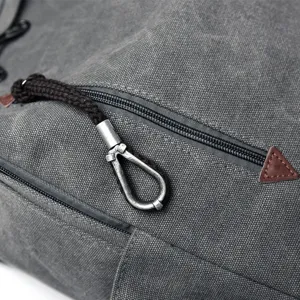 Detailed view of a vintage gray canvas backpack zipper with an antique metal puller loop.