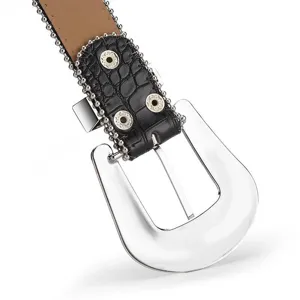 Macro detail of western punk style belt buckle with silver beads and black faux crocodile leather