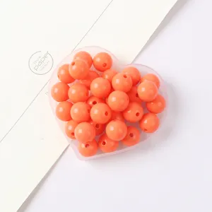 Close-up detail of vibrant orange acrylic round beads in a heart box for DIY craft projects.