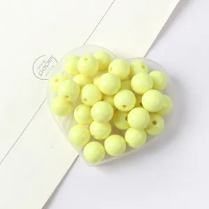 Detail view of yellow acrylic round beads, smooth surface with straight hole for DIY crafts.