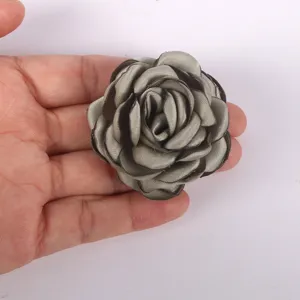 Vue détaillée d'une fleur de rose en tissu gris faite à la main pour travaux manuels et broches.