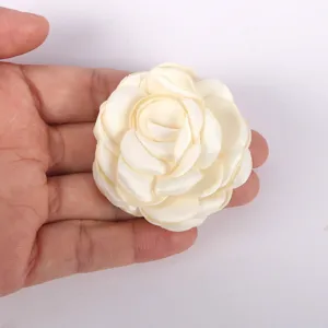 Gros plan détaillé de fleur de camélia en tissu blanc crème, texture à bords brûlés.