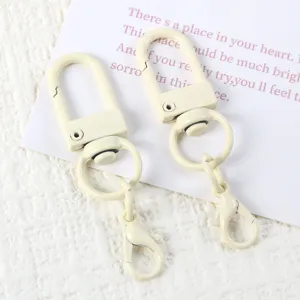 Detailed shot of DIY U-shaped swivel clasp and lobster claw keychain accessories in cream white.