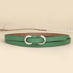 Detail of slim green leather belt with a silver infinity-shaped metal buckle