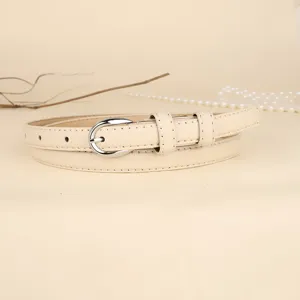 Detail view of a minimalist beige slim leather belt with a silver oval metal buckle