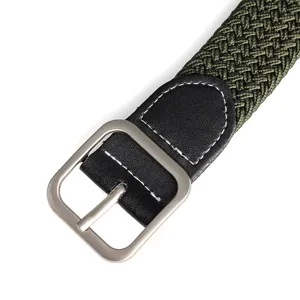 Close-up detail of green woven stretch belt with metal pin buckle and leather tip.