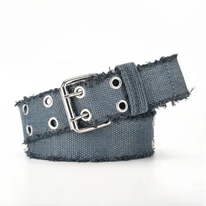 Detailed closeup of grey canvas belt featuring double grommets and frayed edges for unique style.