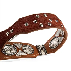 Dettaglio di cintura in pelle marrone vintage con ornamenti e borchie in metallo argentato.